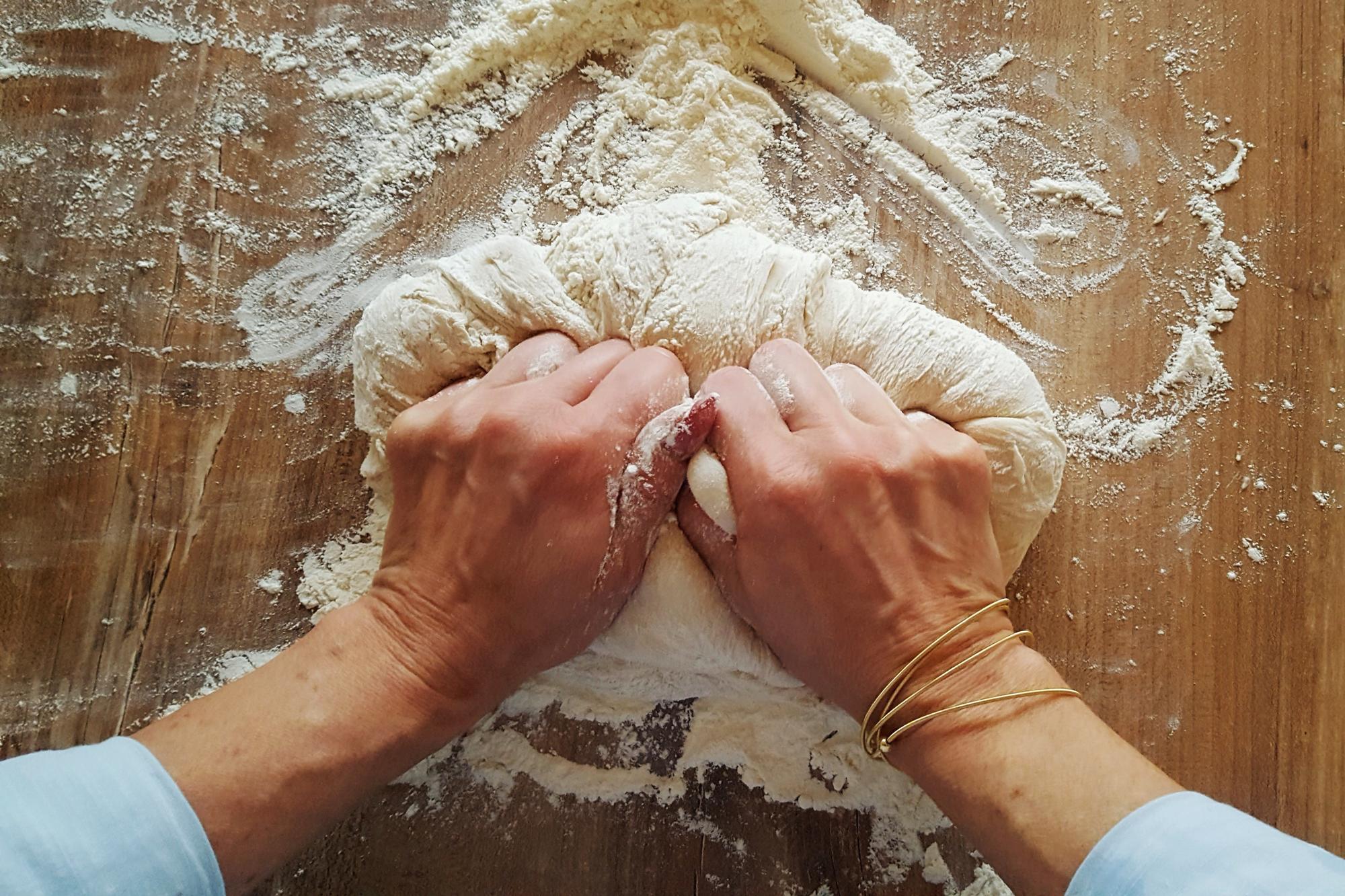 Hands kneading dough in workshop